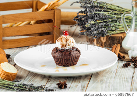 Chocolate muffin with a ball of ice cream  66897667