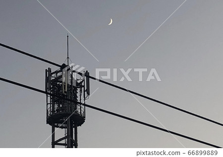 A landscape with a gray sky at night, a steel tower, a steel wire, and a crescent moon 66899889