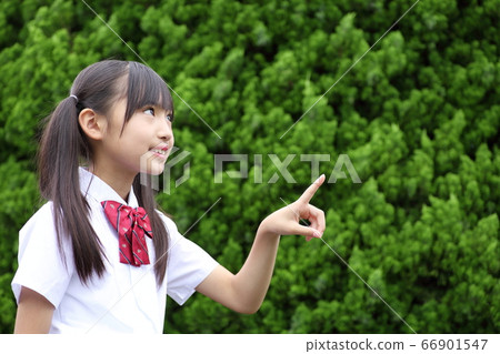 Elementary school student pointing at green background Elementary school student pointing at green background 66901547