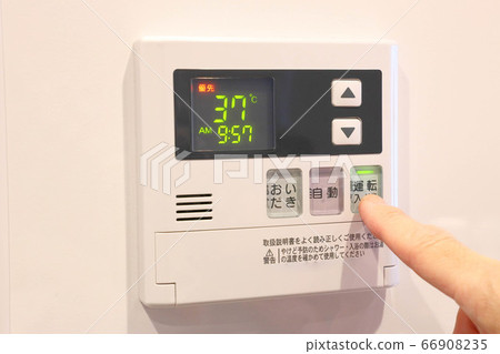 Finger pressing the switch panel of the water heater 66908235