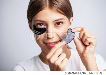Young woman with beautiful skin puts black patches on her face 66909183