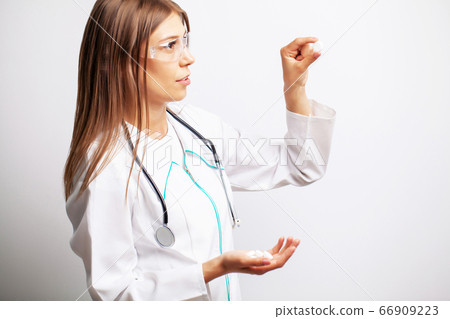 Young female doctor holding a pill of vitamins 66909223
