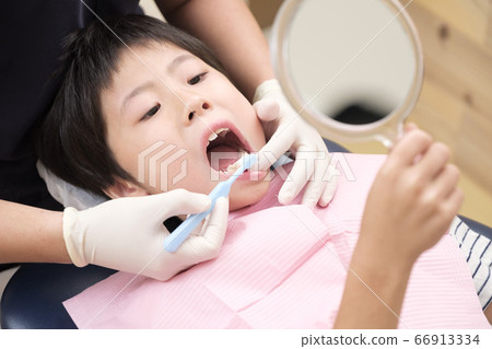 Child receiving tooth brushing instruction at the dentist 66913334
