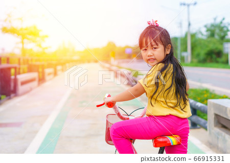Little child girl to ride bicycle in outdoor sports ground on sunny summer day. Little child girl to ride bicycle in outdoor sports ground on sunny summer day. 66915331