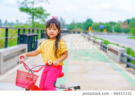 Little child girl to ride bicycle in outdoor sports ground on sunny summer day. Little child girl to ride bicycle in outdoor sports ground on sunny summer day. 66915332