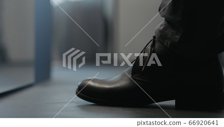 Young man put on his brown leather chukka boots indoor 66920641