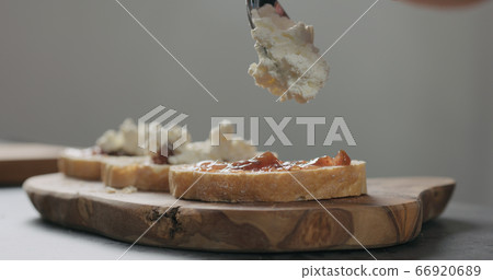 Slow motion man add ricotta to slice of ciabatta with fig marmalade and pancetta 66920689