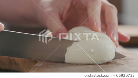 man slicing mozzarella ball on olive wood board man slicing mozzarella ball on olive wood board 66920732