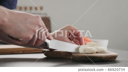 man slicing mozzarella ball on olive wood board man slicing mozzarella ball on olive wood board 66920734