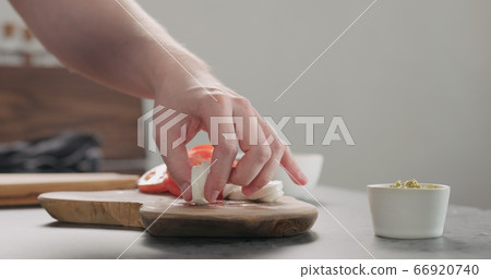 man slicing mozzarella ball on olive wood board 66920740