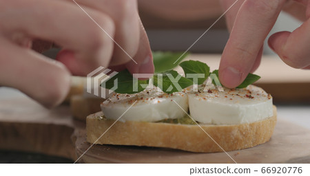 man decorating bruschetta with pesto and mozzarella on olive board man decorating bruschetta with pesto and mozzarella on olive board 66920776
