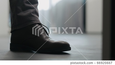 Young man put on his brown leather chukka boots indoor 66920887