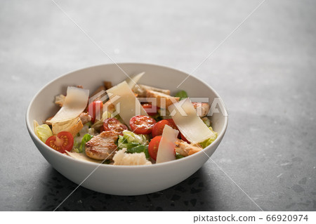 Fresh caesar salad with chicken and cherry tomatoes in white bowl 66920974