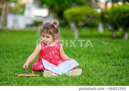 Little  girl learning for coloring or drawing paint on green grass in nature at garden 66921593