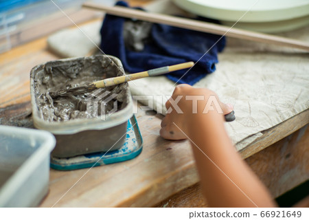 Motion blurred hands of girl molding the clay work with wet mud in plastic tray 66921649