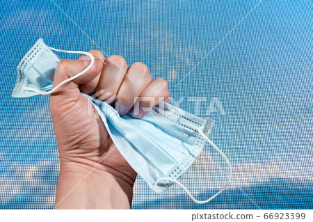 Hand clutching a medical mask Hand clutching a medical mask 66923399