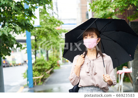Time lag work A business woman wearing a rain mask and holding an umbrella Work at work Commuting Time lag work A business woman wearing a rain mask and holding an umbrella Work at work Commuting 66923583