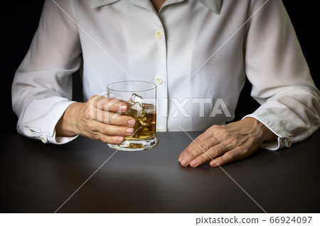 close-up of a woman's hands with a glass of Scotch close-up of a woman's hands with a glass of Scotch 66924097