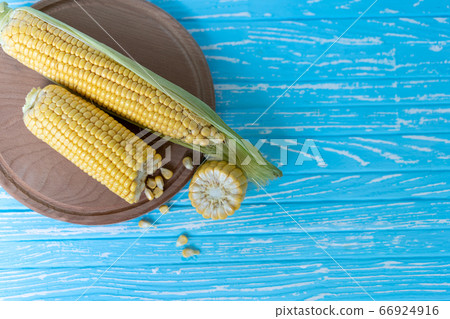 Corn cob with green leaves lies on Round cutting Corn cob with green leaves lies on Round cutting 66924916