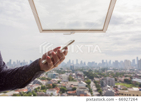 A man uses a phone against the backdrop of a panorama of a metropolis. A man uses a phone against the backdrop of a panorama of a metropolis. 66927264