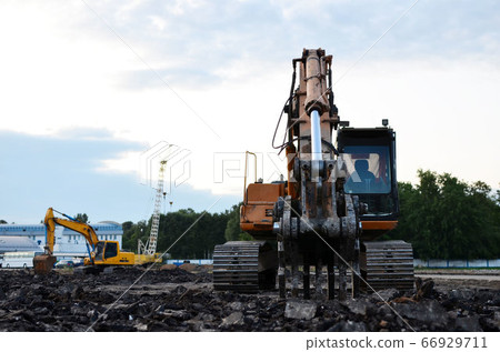 Excavator with hydraulic shears at construction site against the background sunset. 66929711