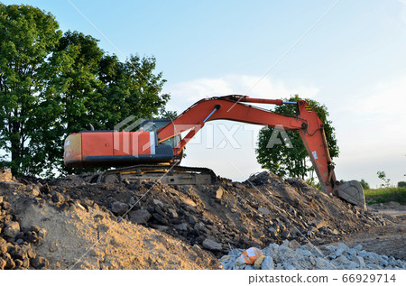 Excavator with a large iron bucket on a construction site during road works 66929714