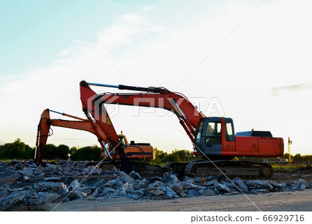 Crawler excavator with hydraulic breaker hammer on sunset. 66929716