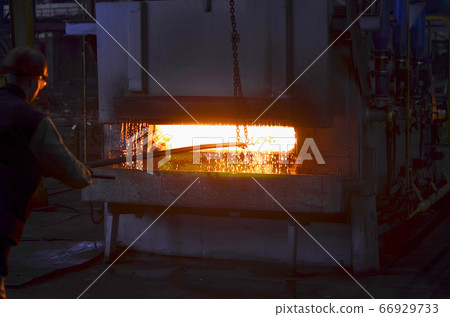Steel quenching at high temperature in industrial furnace at the workshop of a forge plant. 66929733