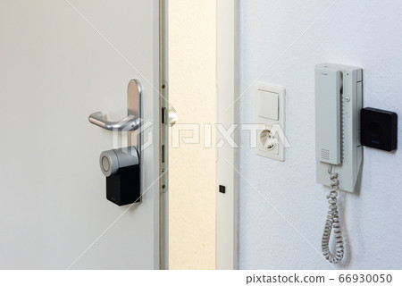 Entrance door being equipped with a Nuki Smartlock and door opener. Concept of using smart electronic locks with keyless access Entrance door being equipped with a Nuki Smartlock and door opener. Concept of using smart electronic locks with keyless access 66930050