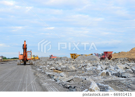 Excavator with a hydraulic hammer and shears destroys the road surface and pavement. Excavator with a hydraulic hammer and shears destroys the road surface and pavement. 66931415