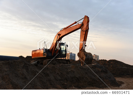 Red excavator at building under construction against the background sunset 66931471