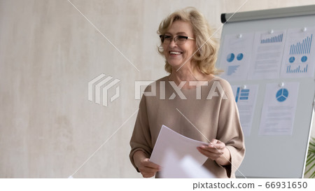Head shot smiling middle aged businesswoman mentor standing in boardroom Head shot smiling middle aged businesswoman mentor standing in boardroom 66931650