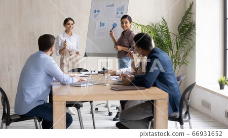 Smiling Indian and Arabic businesswomen giving flip chart presentation Smiling Indian and Arabic businesswomen giving flip chart presentation 66931652