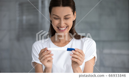 Happy young woman excited with positive pregnancy test result 66933846