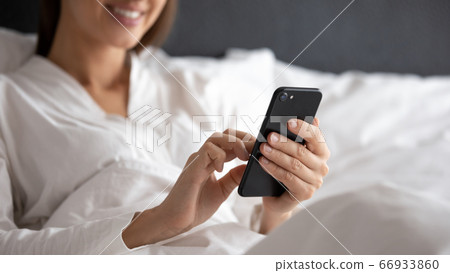 Close up of woman relax in bed using cellphone 66933860