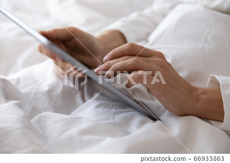 Close up of woman using tablet in bed Close up of woman using tablet in bed 66933863