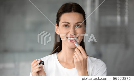 Beautiful young woman look in mirror coloring lips Beautiful young woman look in mirror coloring lips 66933875