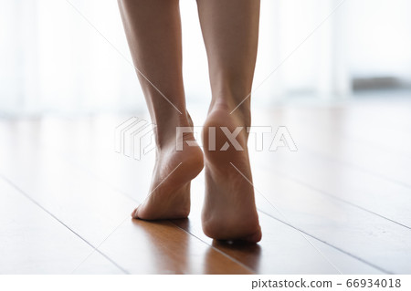Close up of woman walk barefoot on wooden floor 66934018