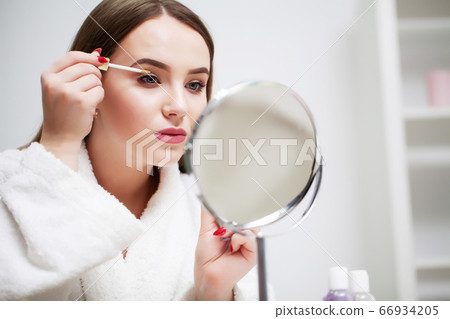 Pretty girl applies makeup on her face in the hotel bathroom Pretty girl applies makeup on her face in the hotel bathroom 66934205