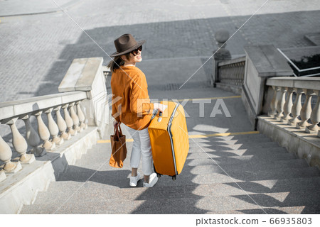 Woman traveling with a suitcase in the old city 66935803