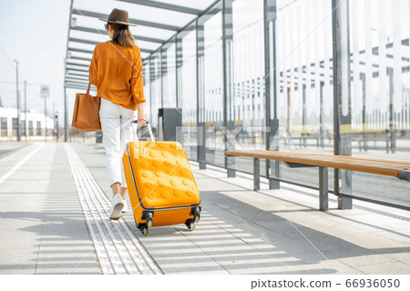 Young female traveler with a luggage at the transport stop 66936050