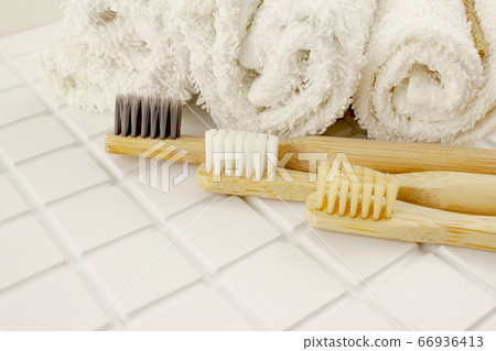 Family set of tree bamboo toothbrushes, white towels on tile background. Eco friendly concept Family set of tree bamboo toothbrushes, white towels on tile background. Eco friendly concept 66936413