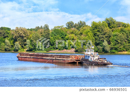 A river tug is pushing a rusty barge A river tug is pushing a rusty barge 66936501