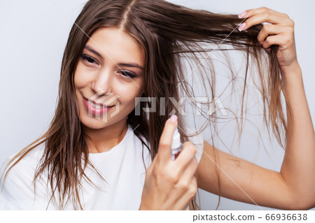 Young beautiful woman applies conditioner on damaged hair to restore and care for hair 66936638