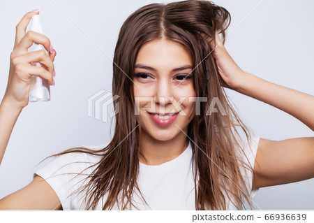 Young beautiful woman applies conditioner on damaged hair to restore and care for hair 66936639