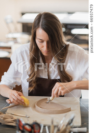 Close-up of potter making pot in pottery workshop. Using sponge and water for moisturizing clay. Close-up of potter making pot in pottery workshop. Using sponge and water for moisturizing clay. 66937479