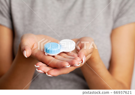 Vision problems, close up of woman holding container with contact lenses 66937621