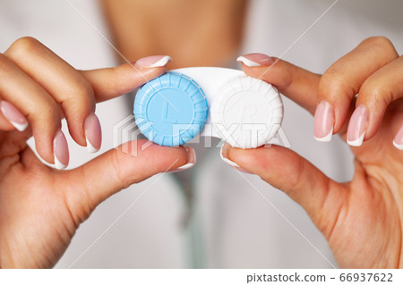 Vision problems, close up of woman holding container with contact lenses 66937622