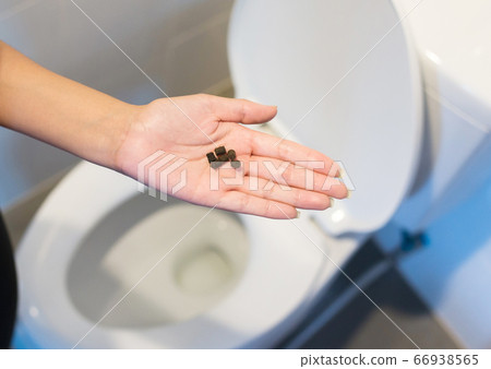 Woman hands holding laxatives pill and using toilet and suffers from diarrhea and hemorrhoids after wake up in the morning Woman hands holding laxatives pill and using toilet and suffers from diarrhea and hemorrhoids after wake up in the morning 66938565