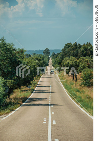 Road with lonely car through rural landscape Road with lonely car through rural landscape 66938639